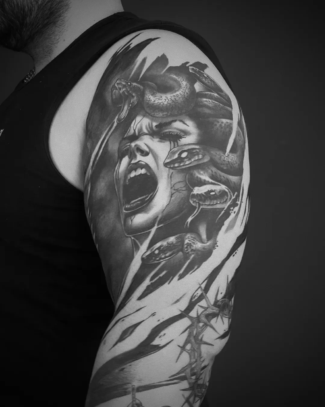 Realistic-Tattoo: schreiende Medusa mit Schlangenhaar auf dem Oberarm